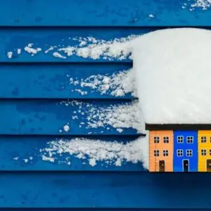 A blue house with snow on the top of it.