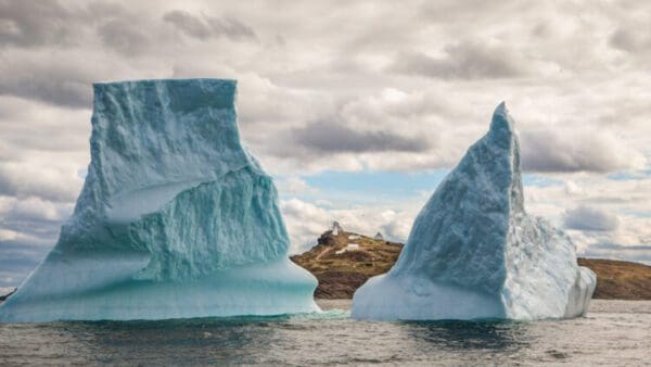 Two large icebergs in the ocean with a boat on it.