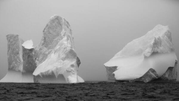 Two large icebergs in the ocean with a sky background