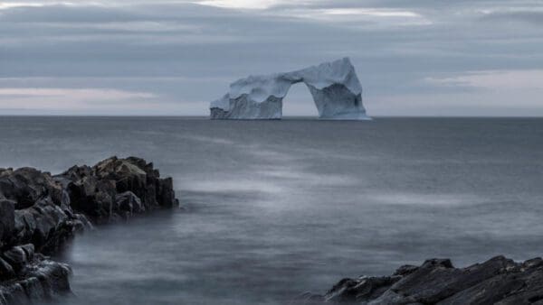A large iceberg in the middle of an ocean.