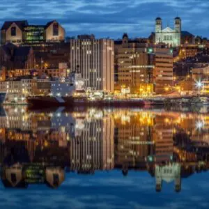 A city skyline with buildings lit up at night.
