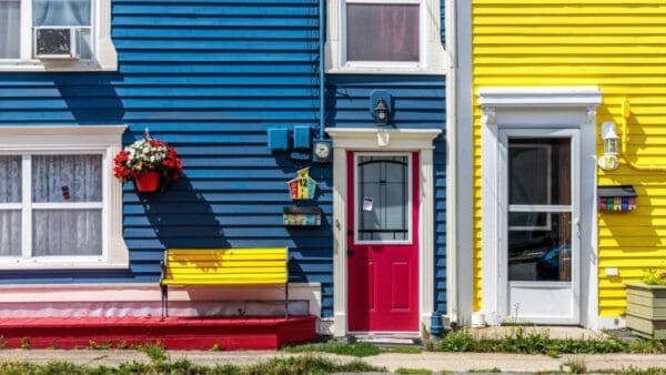 A colorful house with a red door and yellow bench.